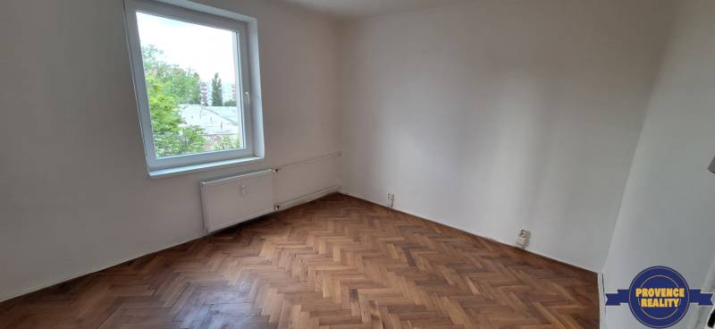 An empty room with a parquet floor and a window in a 3-room apartment.