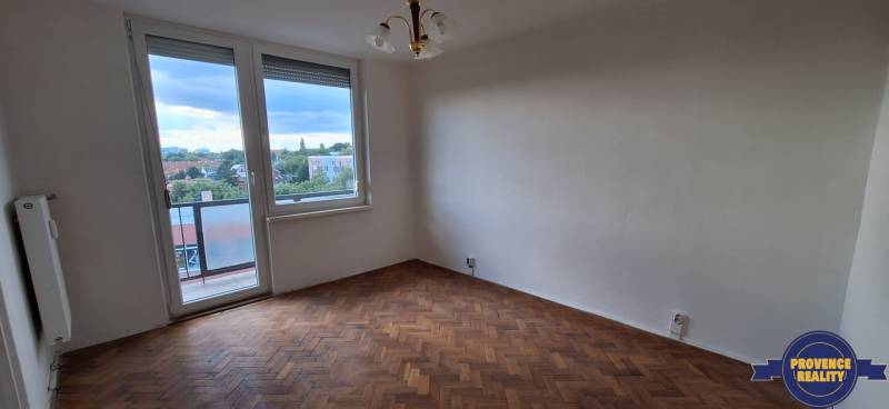 A room in a 3-room apartment with a wooden floor, balcony, city view.