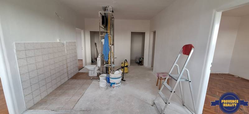 Interior of a 3-room apartment before renovation with a ladder, buckets, and tools.