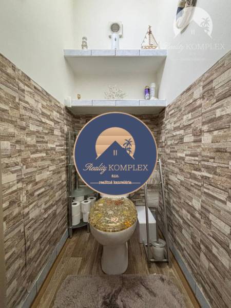 A toilet in a family house with wooden paneling and a decorative seat.