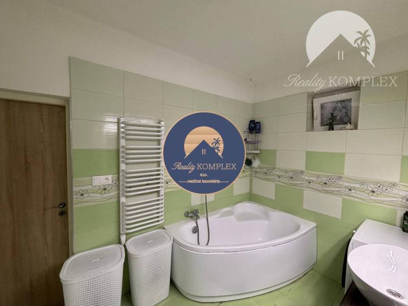 A bathroom in a family house with a corner bathtub and green tiles.