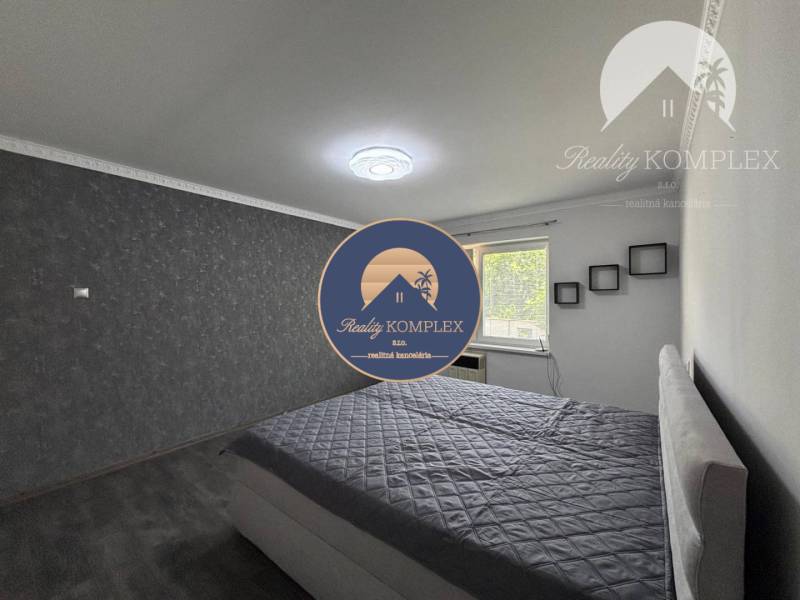 A bedroom in a family house with an upholstered bed and a gray wall.
