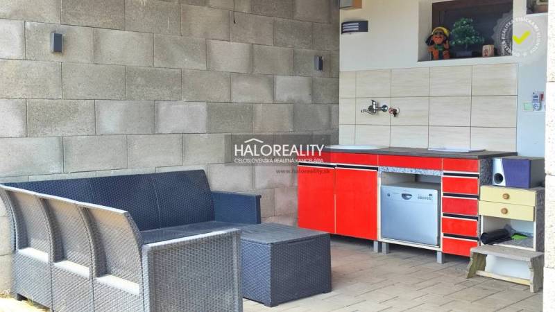 Seating and kitchenette in the gardens in Lučenec. Rattan furniture and a red cabinet.