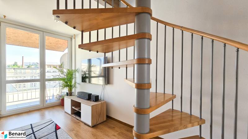 A spiral staircase in a 4-room apartment is complemented by a television, windows, and a plant.