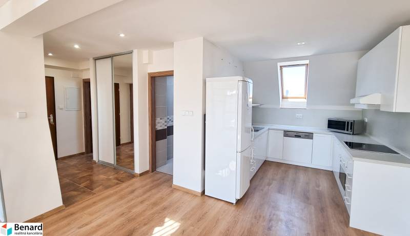 A kitchen with white cabinets and appliances in a 4-room apartment with wooden flooring.