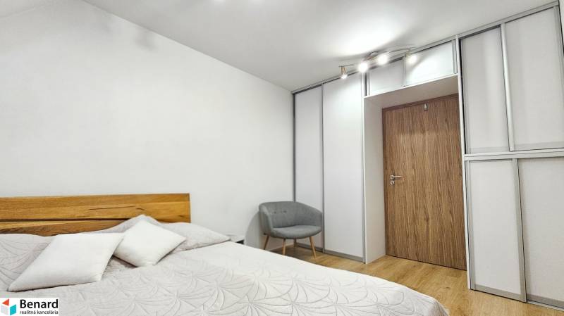 A bedroom with a bed, an armchair, and a built-in wardrobe in a 4-room apartment.