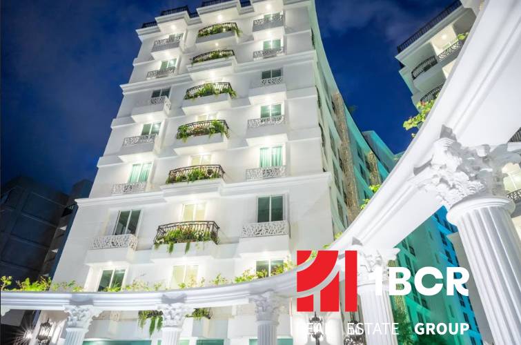 A building under construction of apartments in Pattaya with a white facade and balconies with plants.