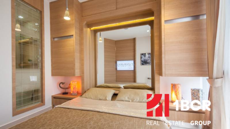 A stylish bedroom in a 2-room apartment with wooden elements and a large mirror.