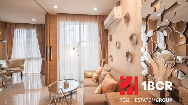 Living room of a two-room apartment with a bright interior, mirrors, and decorative pillows.