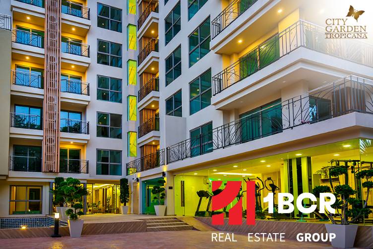 Apartment construction in Pattaya: a modern building with glass balconies and night lighting.