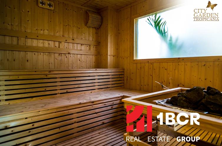 Wooden sauna with a glass window and the real estate agency's logo.