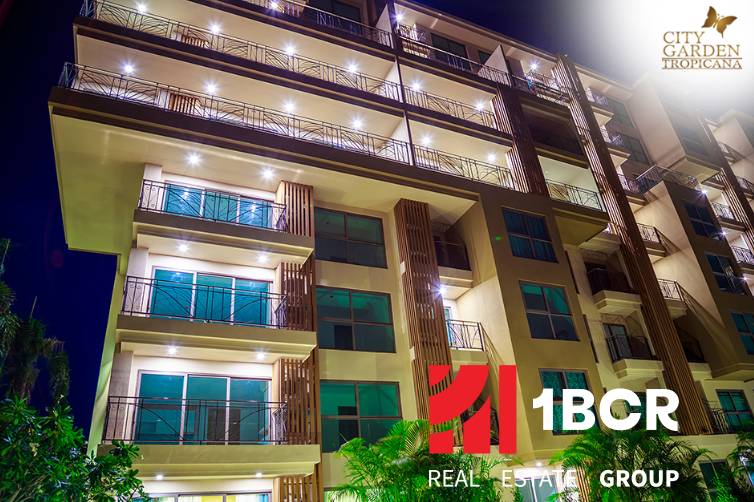 Apartment construction in Pattaya with an illuminated facade and numerous balconies at night.