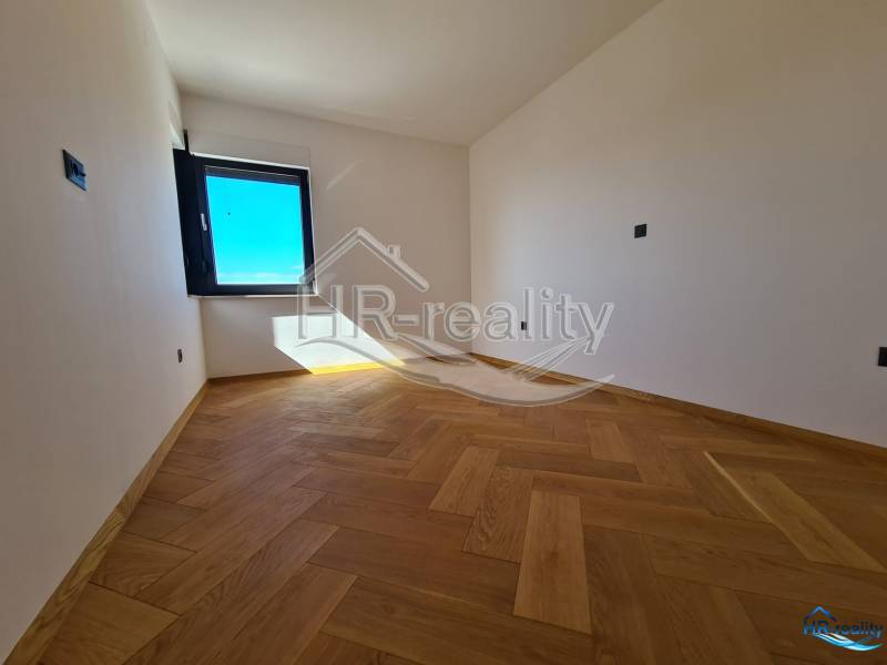 A room with a wooden floor and a large window in a vacation apartment.