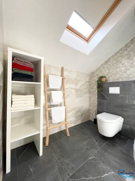 A bathroom in a holiday apartment with a towel shelf and a skylight.