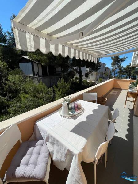 Terrace of a recreational apartment on Šolta, a table with chairs and a view of greenery.