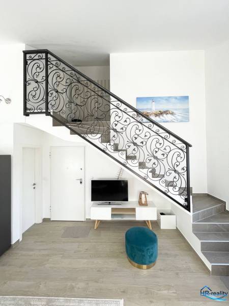 Interior of a holiday apartment with a television, staircase, and decorative railing.
