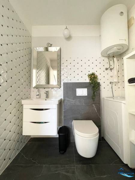 Bathroom in a holiday apartment with storage space, mirror, and washing machine.