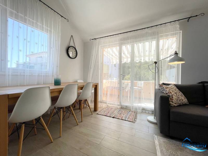 The holiday apartment offers a bright living space with a dining table and a comfortable sofa.