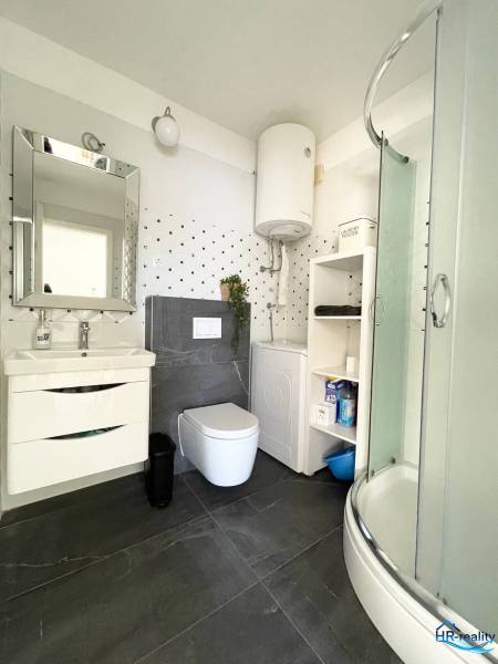 Bathroom in a holiday apartment with toilet, shower, sink, and boiler.