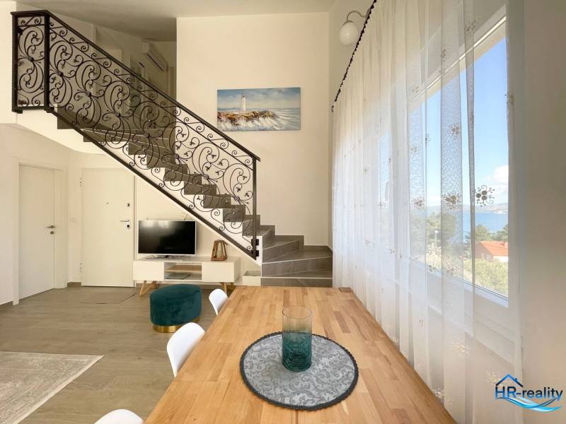 A recreational apartment with a wrought iron staircase and dining table, sea view.