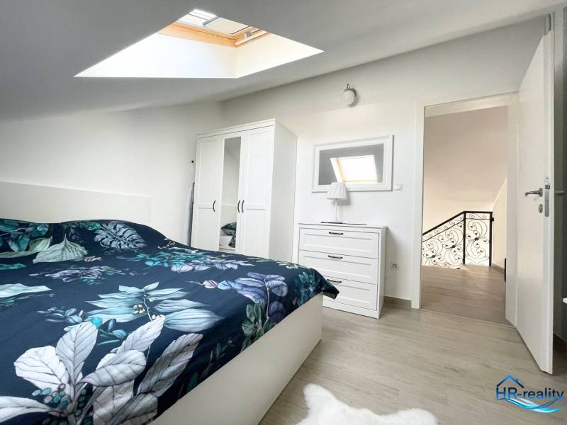 A bedroom in a holiday apartment with a bed, wardrobe, and skylight.