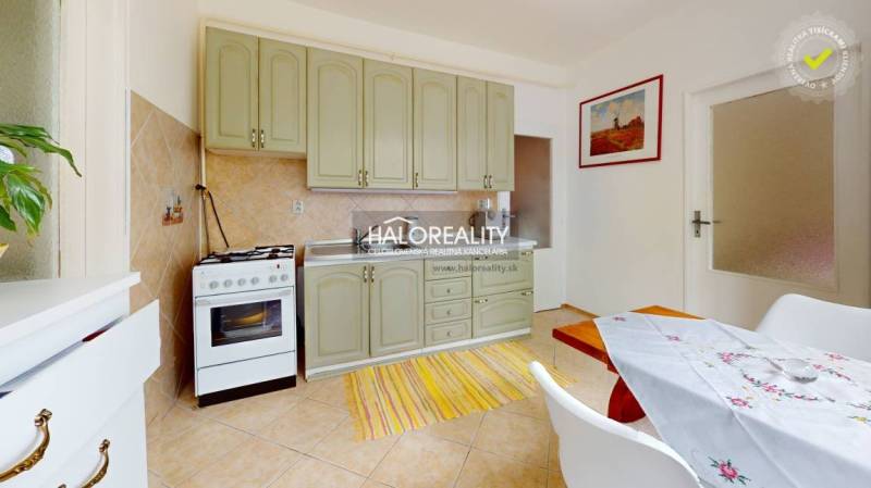 The kitchen of a 4-room apartment with light cabinets, a dining table, and an oven.