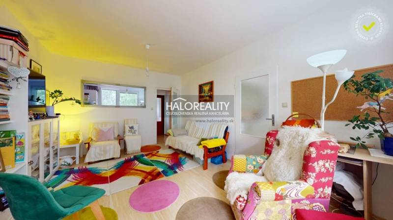 A colorful living room in a 4-room apartment with various patterned chairs and decorations.