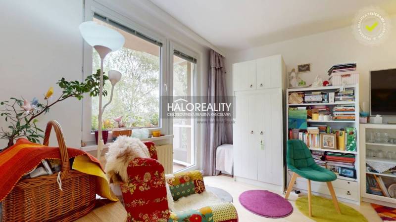 A colorful interior of a 4-room apartment with books and a comfortable armchair by the window.