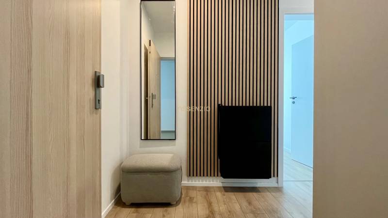 A hallway with wooden paneling and a mirror in a 2-room apartment.