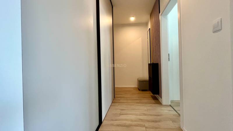A hallway in a 2-room apartment with light wooden floors and white walls.
