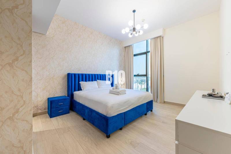 Bedroom in a 3-room apartment with a blue bed, dresser, and modern lighting.