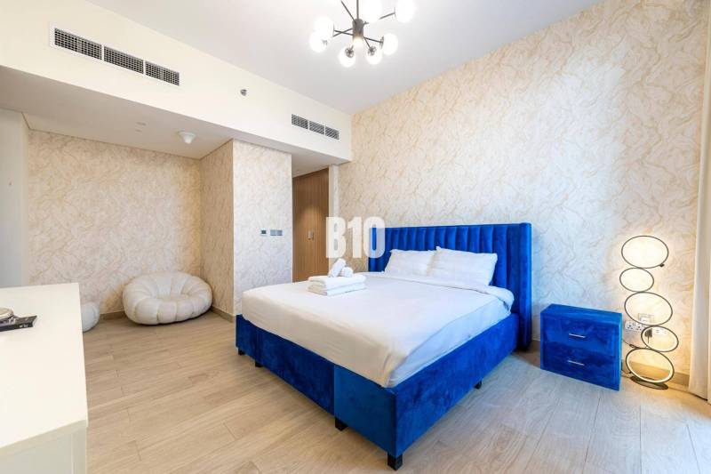 A bedroom with a blue bed and subtly patterned walls in a 3-room apartment.