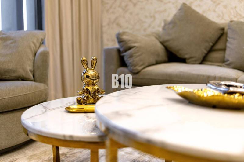 A golden rabbit statue on a marble table in a 3-room apartment with a comfortable gray sofa.