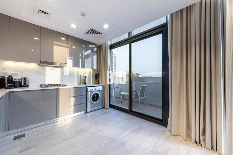 A kitchen in a 3-room apartment with a washing machine and a balcony, light cabinets, large window.