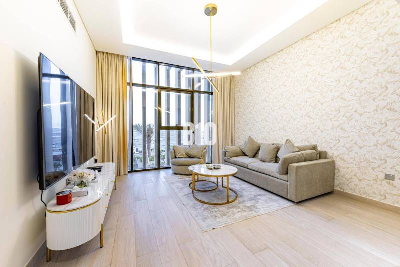 Living room in a 3-room apartment with large windows, a sofa, and a television on a wooden floor.