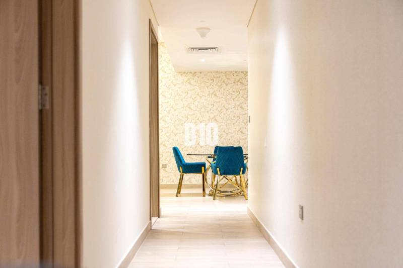 The hallway leads to a room with blue chairs and a patterned wall in a 3-room apartment.