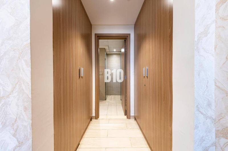 A narrow hallway with built-in wooden wardrobes and a view into the bathroom in a 3-room apartment.
