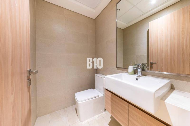A bathroom in a 3-room apartment with light tiles, a mirror, and a sink.