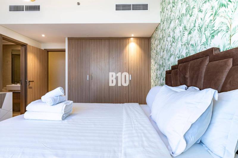 A bedroom with a double bed, a wooden wardrobe, and floral wallpaper in a three-room apartment.