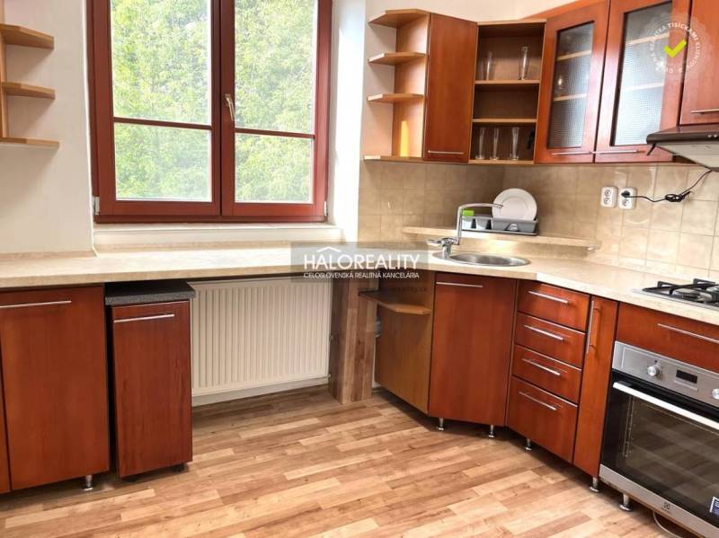 A kitchen in a 3-room apartment with a wooden cabinet, a window overlooking greenery.