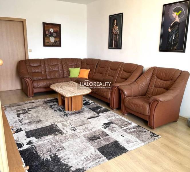 Leather sofa set in the living room of a three-room apartment. Paintings hang on the wall.
