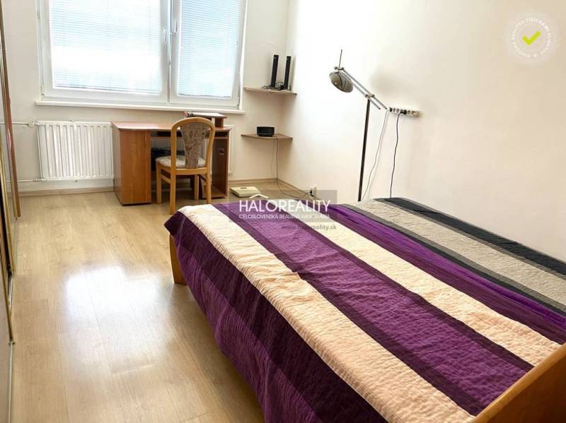Bedroom in a 3-room apartment with a bed, a desk, and wooden flooring.