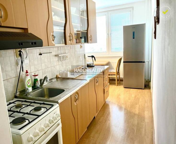 A kitchen with a gas stove and a refrigerator in a 3-room apartment, light-colored countertop.
