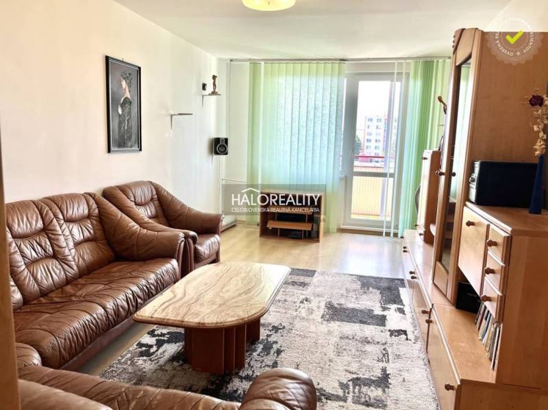 Living room in a three-room apartment with a brown sofa and wooden furniture.