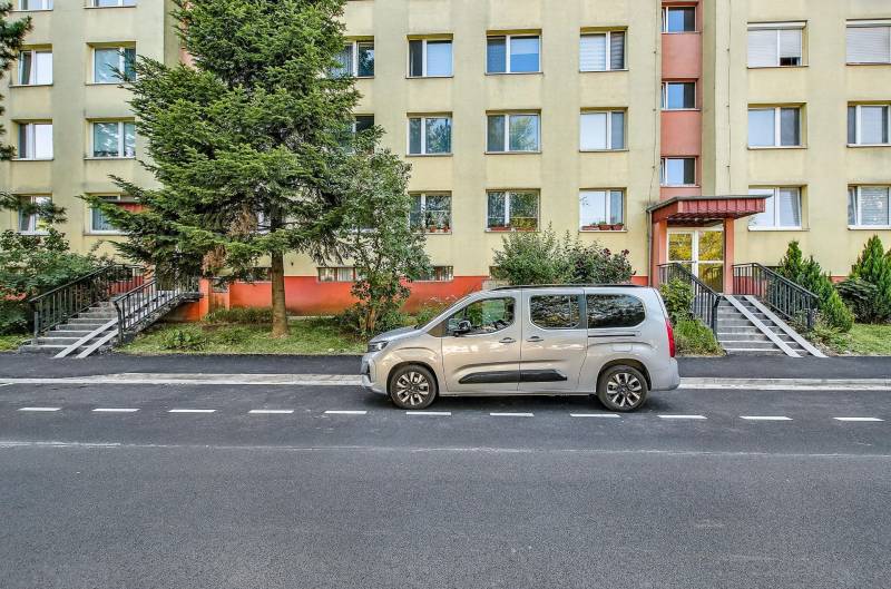 Landau Street in Bratislava-Dúbravka with a residential building and a parked car in front of it.