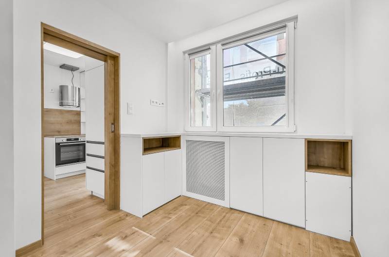 The kitchen of a 4-room apartment with wooden flooring and white cabinets.