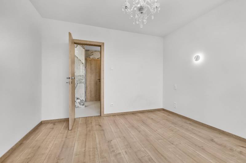 An empty room with a wooden floor and a chandelier in a 4-room apartment.