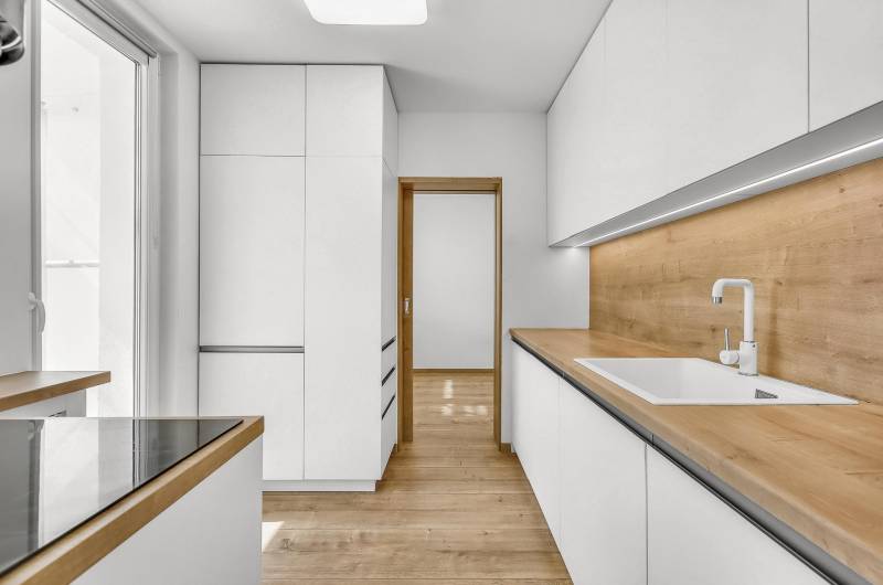 A kitchen in a 4-room apartment with white cabinets and a wooden countertop.