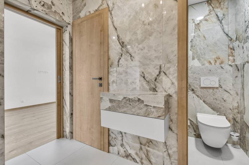 Bathroom with light marble tiles and built-in wall-hung toilet in a 4-room apartment.
