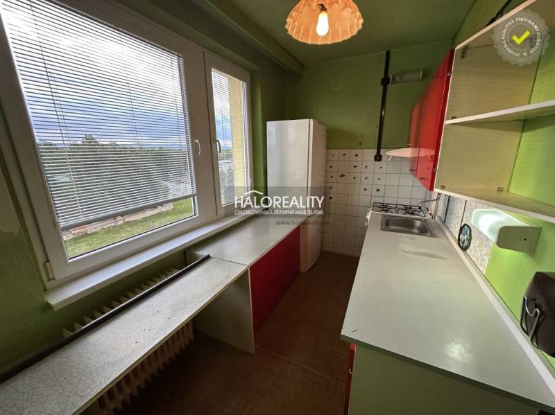 A kitchen in a 3-room apartment with green walls, red cabinets, and a large window.